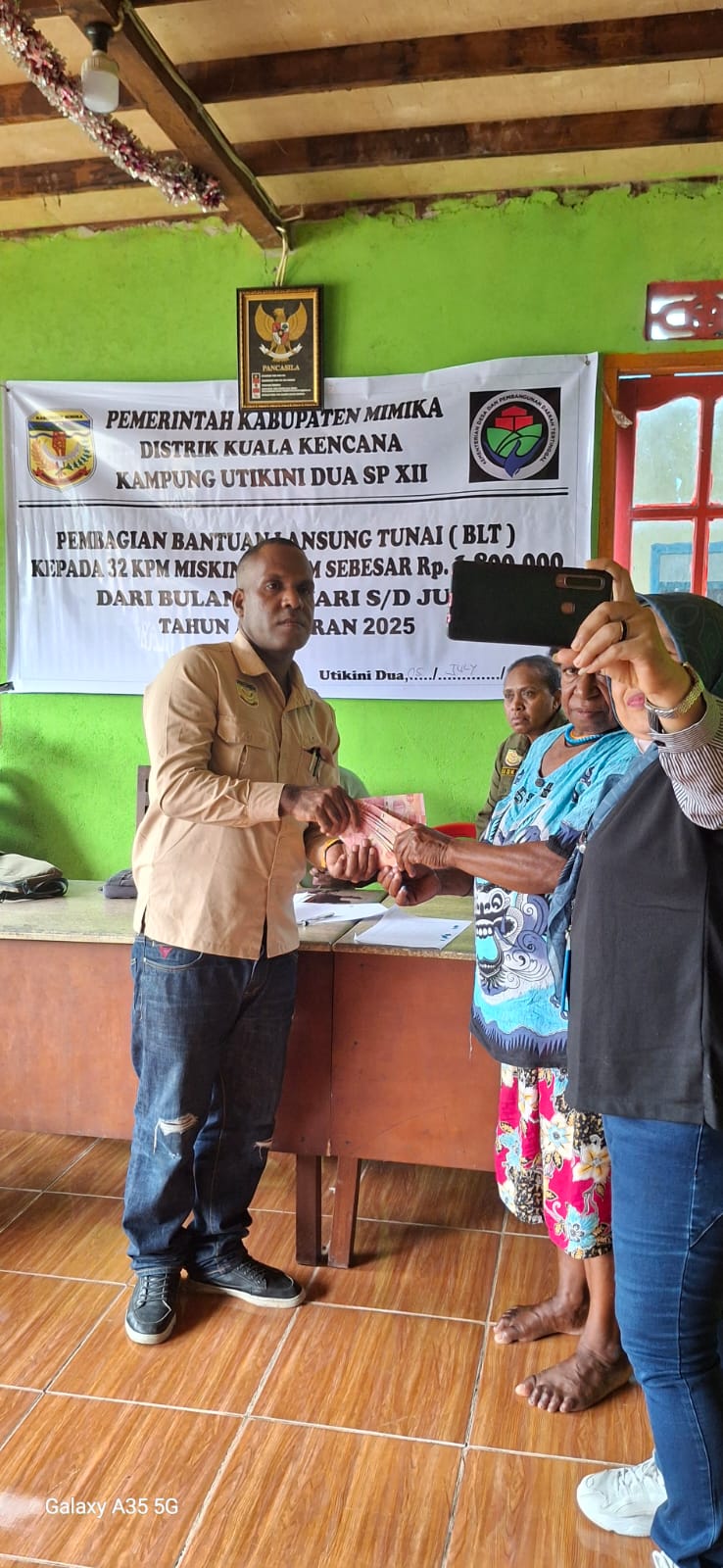 Kepala Kampung Utikini Dua saat menyerahkan Bantuan Langsung Tunai kepada warga