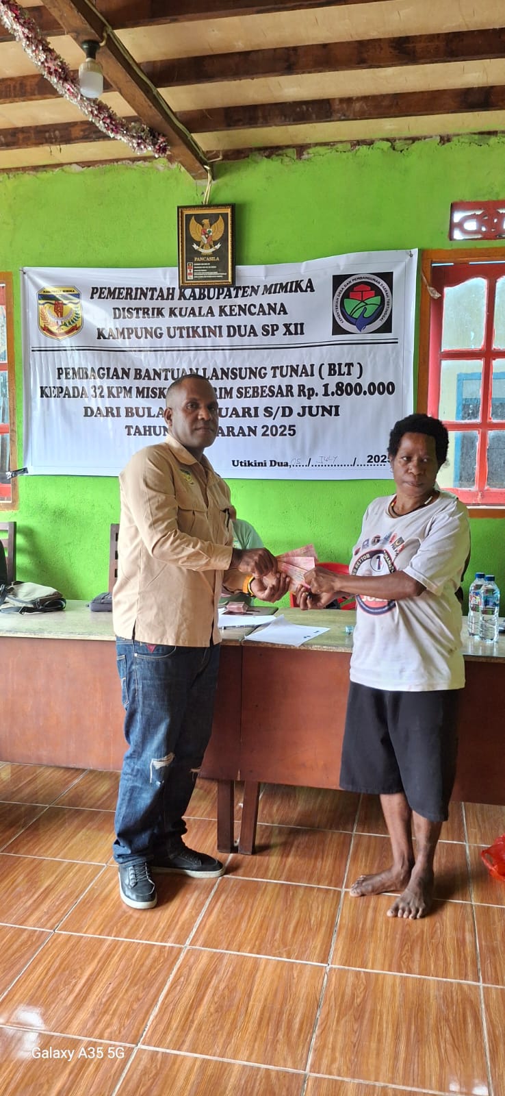 Kepala Kampung Utikini Dua saat menyerahkan Bantuan Langsung Tunai kepada warga