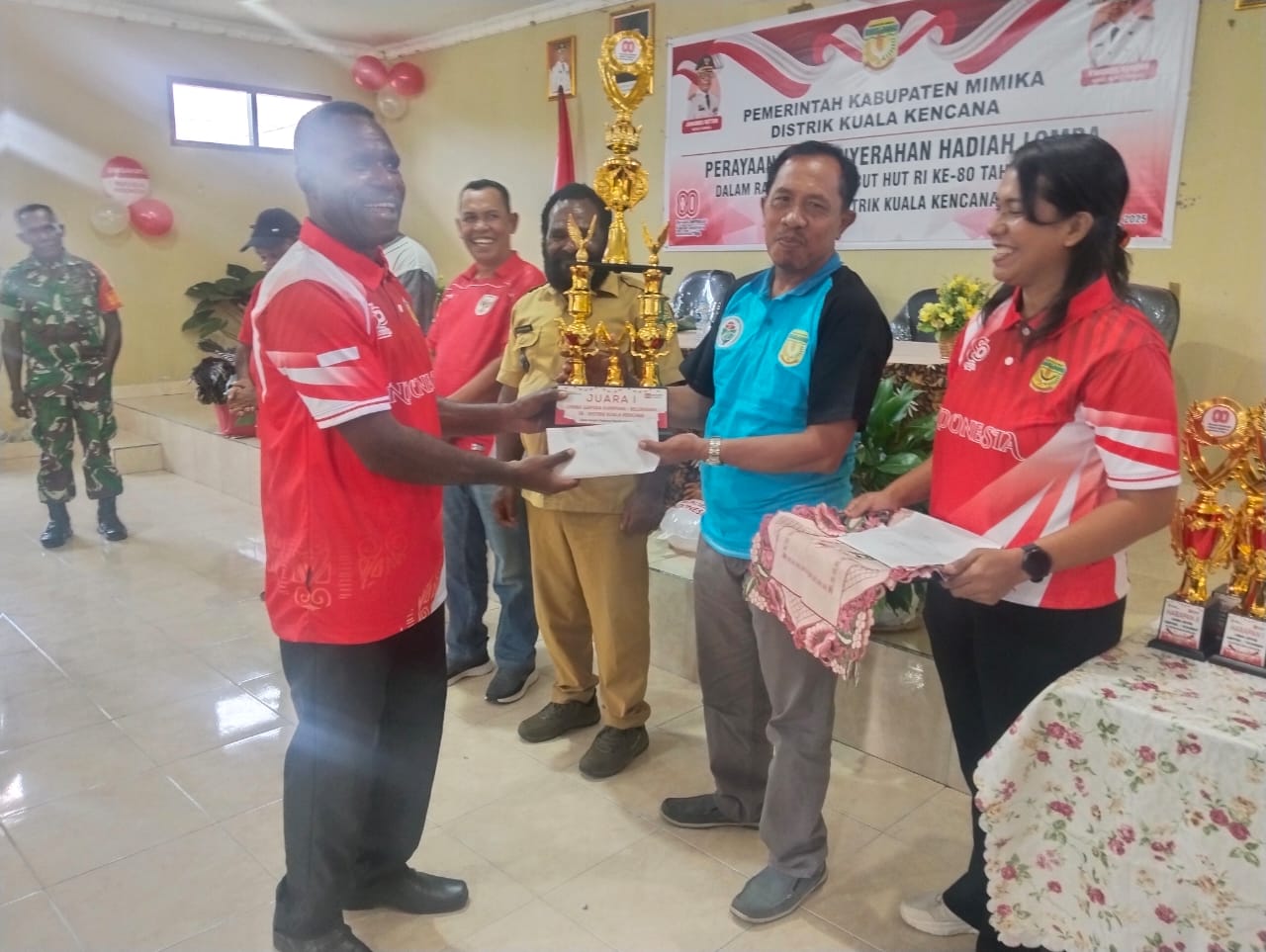 Kepala Distrik Kuala Kencana Yemi Gobai saat menyerahkan piala kepada Kepala Kampung Karya Kencana Rakam Suntoro