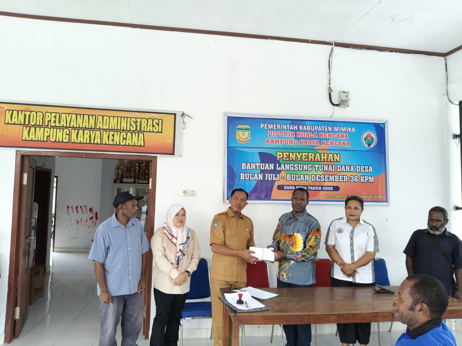 Kepala Distrik Kuala Kencana menyerahkan BLT secara simbolis kepada Kepala Kampung Karya Kencana Rakam Suntoro sebelum dibagikan kepada Keluarga Penerima Manfaat 