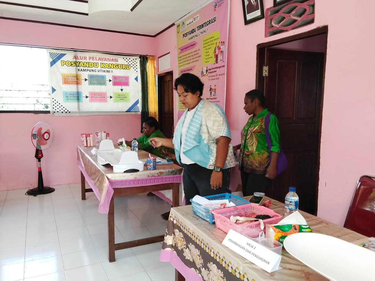 Para kader posyandu dan petugas kesehatan dari puskesmas Bhintuka sedang menyiapkan tempat untuk pelayanan posyandu