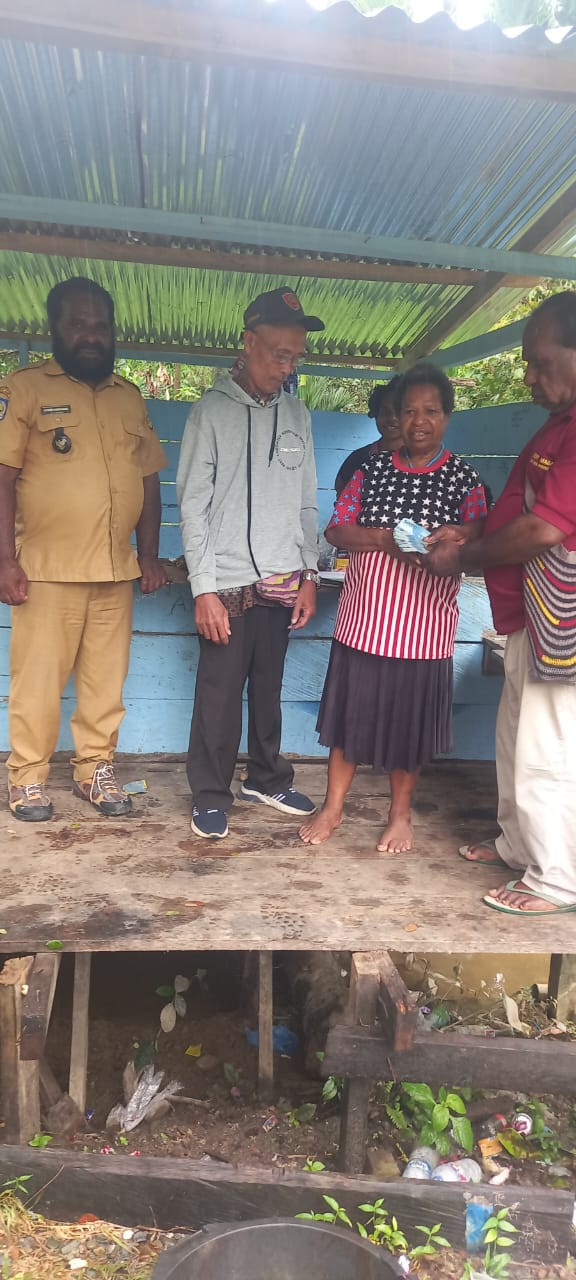 Kepala Kampung Utikini Satu saat menyerahkan Bantuan Langsung Tunai kepada warga