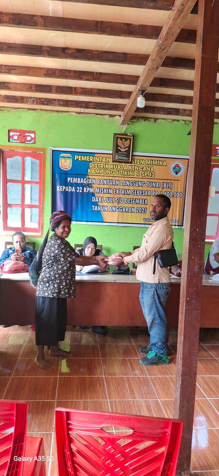 Kepala Kampung Utikini II, Merinus Kogoya didampingi pendamping desa saat menyerahkan BLT kepada seorang warga