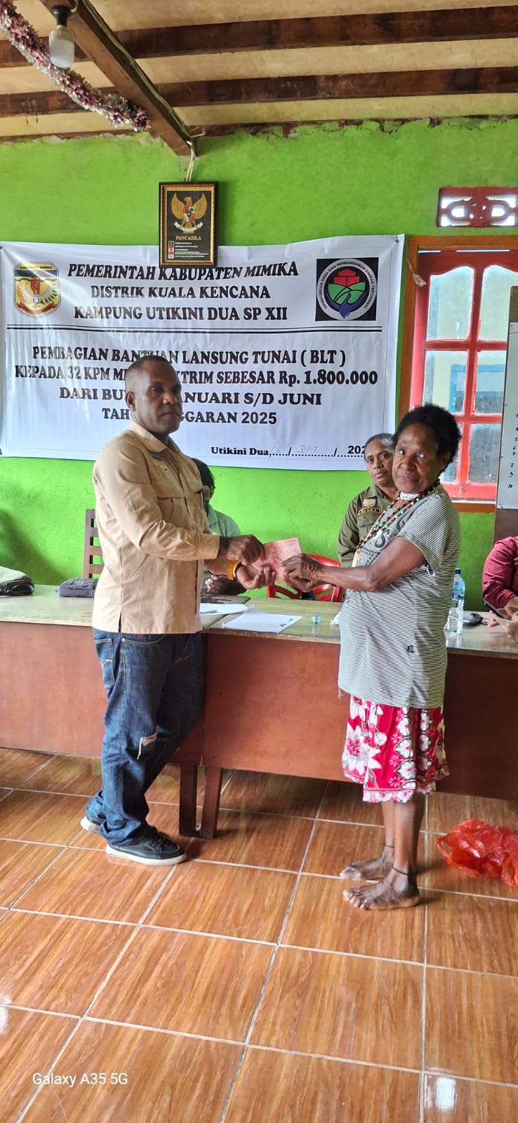 Kepala Kampung Utikini Dua saat menyerahkan Bantuan Langsung Tunai kepada warga