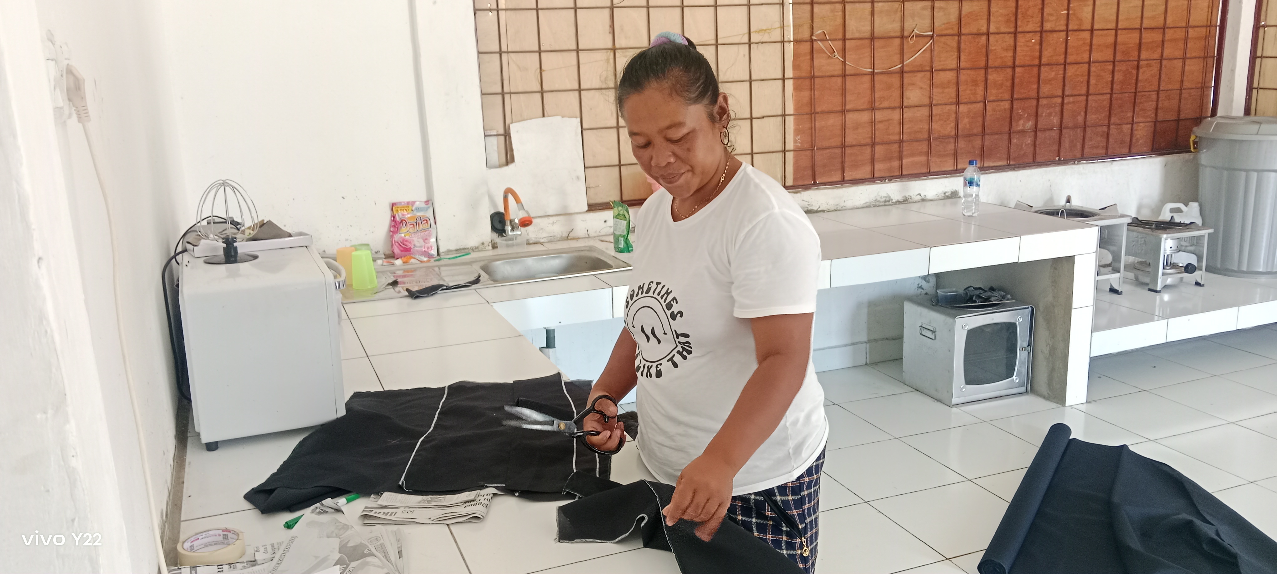 Seorang ibu-ibu PKK saat menggunting kain yang telah diukur