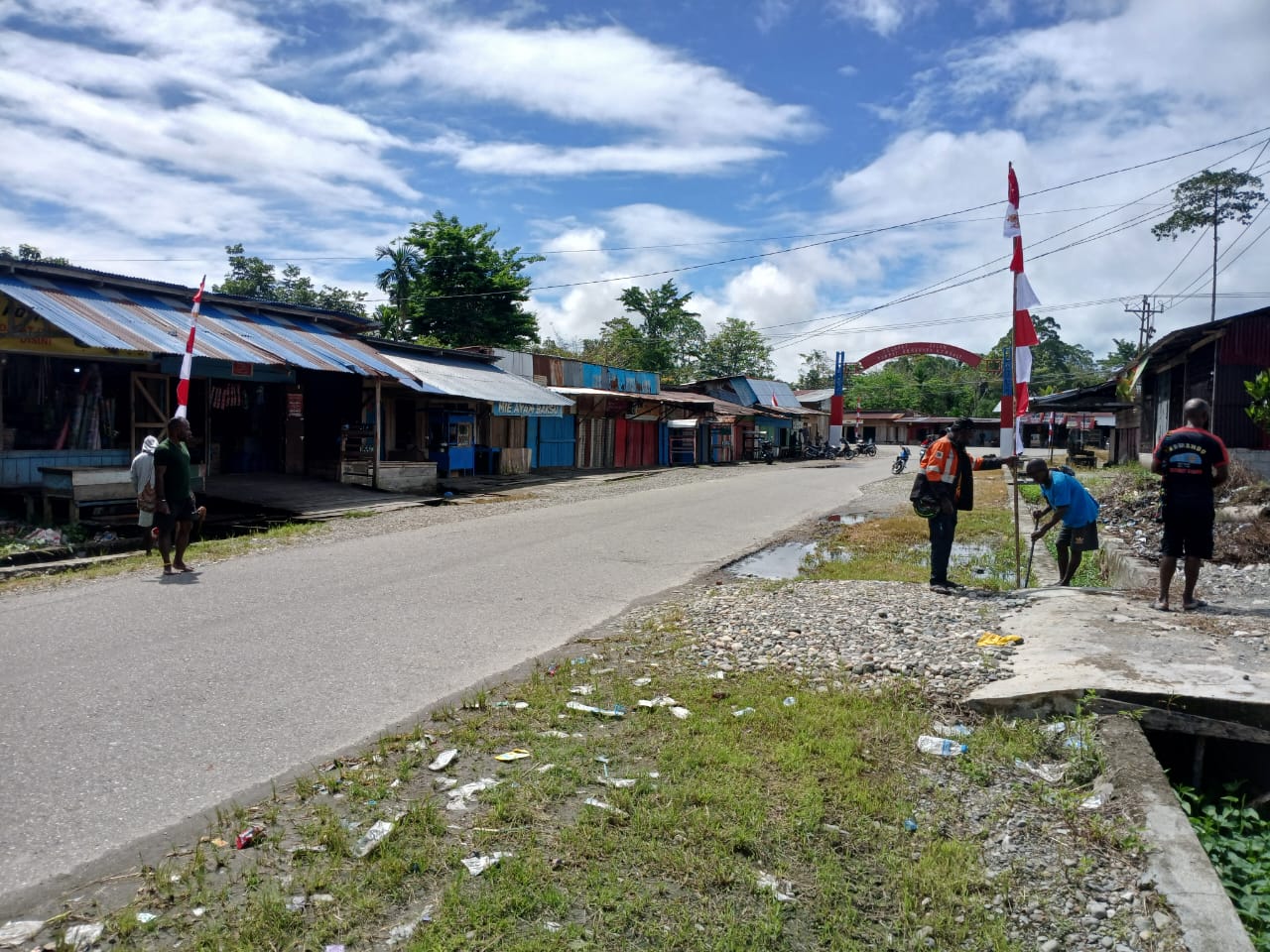 Warga sedang menancapkan tiang bendera di pinggir jalan di Kampung Bhintuka