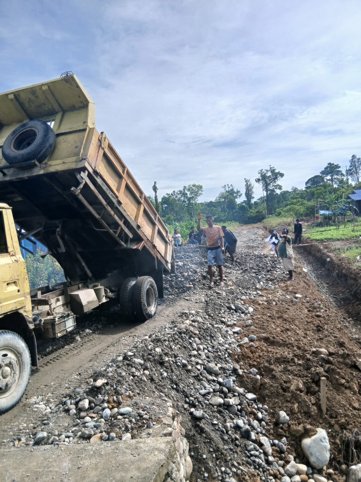 Sebuah truk saat mendumping material timbunan jalan untuk penimbunan jalan kebun 