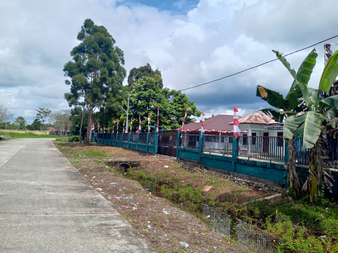 Warga Kampung Mimika Gunung sedang memasang umbul-umbul dipagar Kantor Kampung