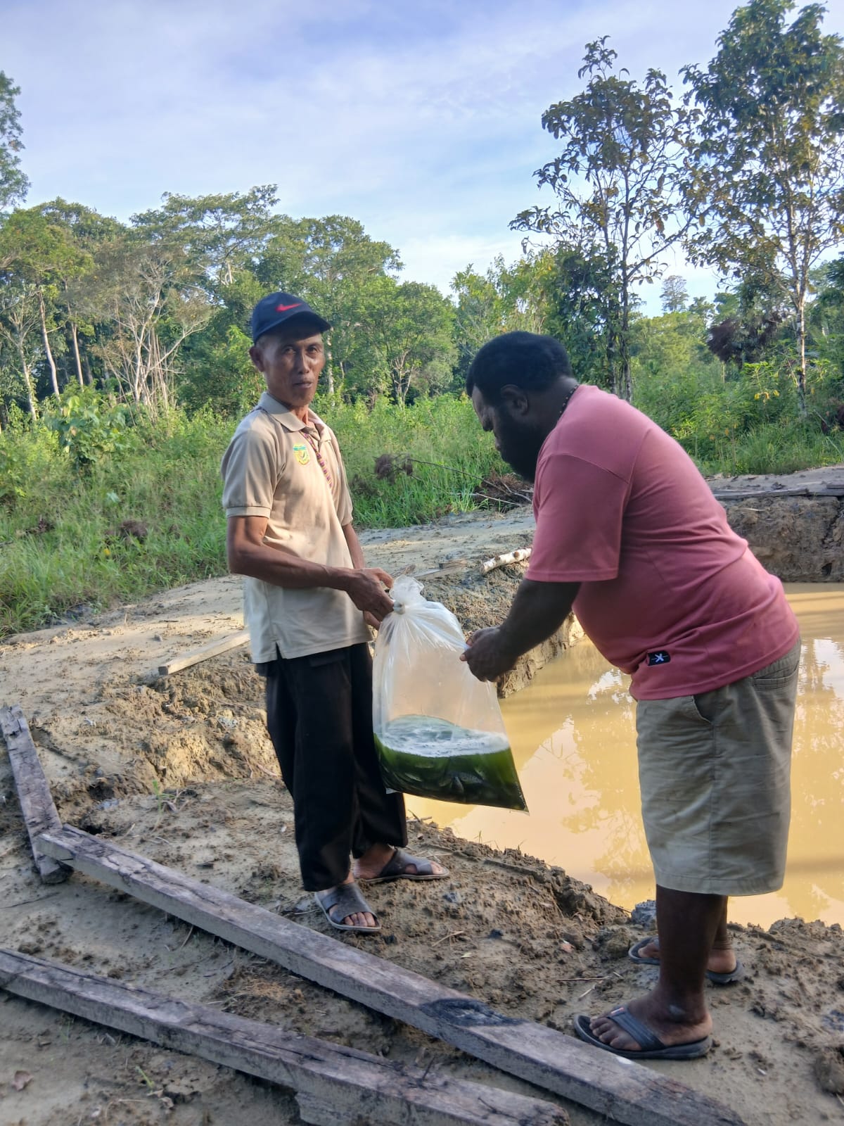 Kepala Kampung Utikini Satu Luther Karagainal bersama sekertaris Kampung Arif Karisto saat melepaskan bibit ikan nila kedalam kolam
