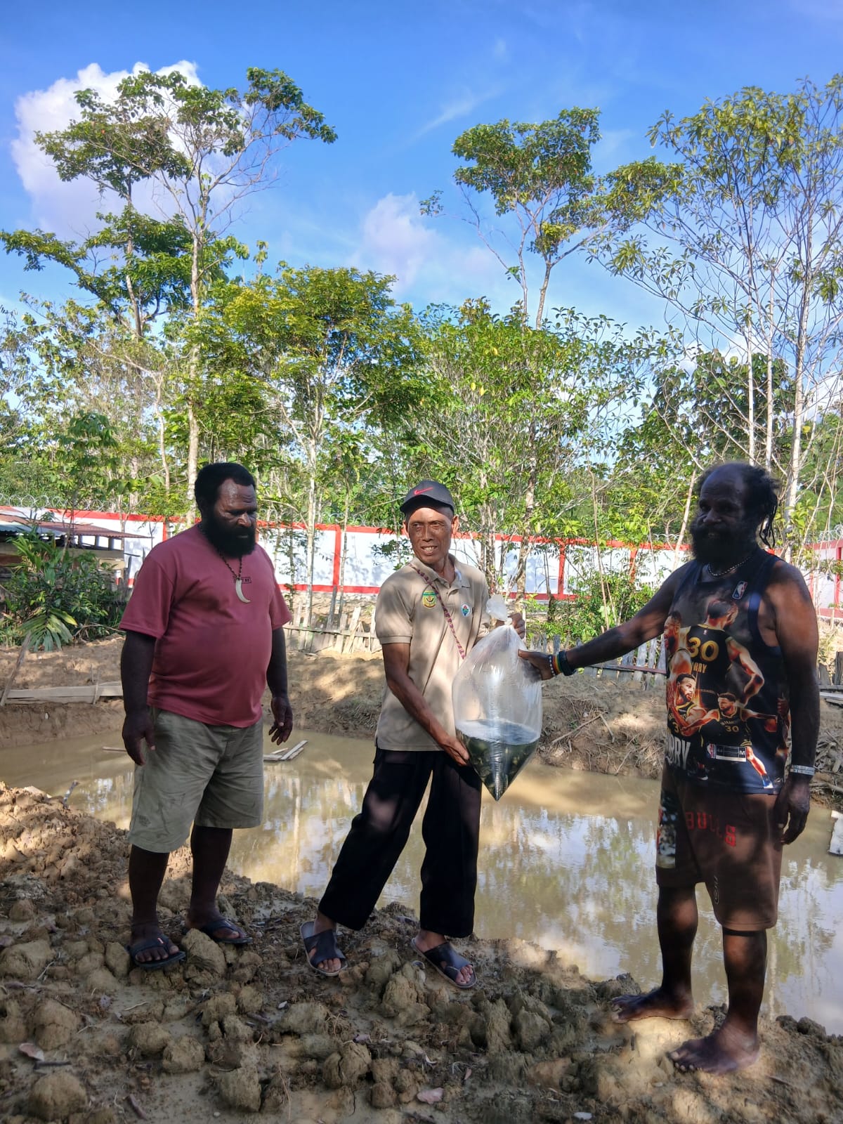Kepala Kampung Utikini Satu Luther Karagainal bersama Sekertaris Kampung Utikini Satu Arif Karisto saat menyerahkan bibit ikan nila kepada warga 