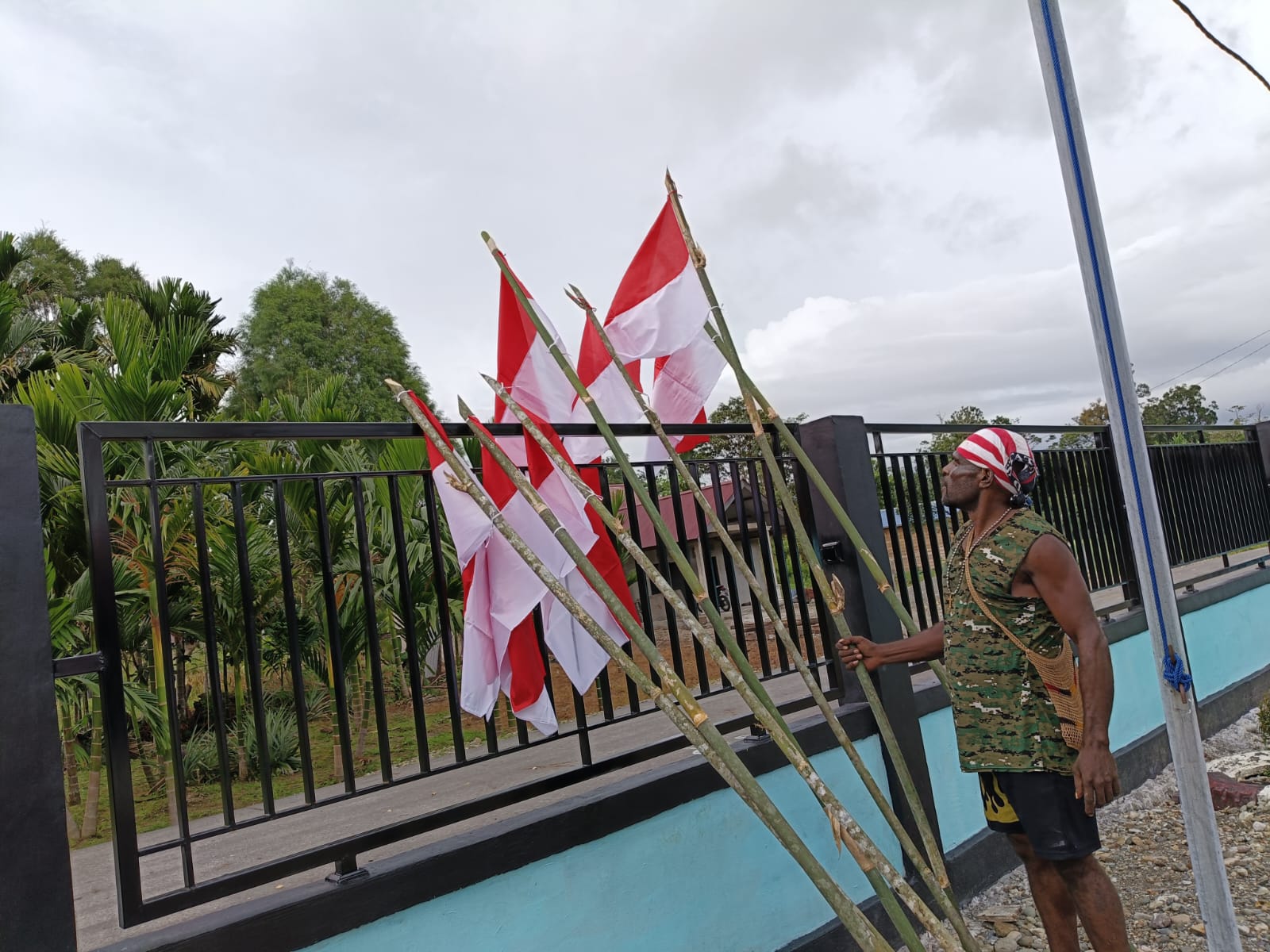 Warga saat mengikat bendera merah putih pada sebuah kayu dan kemudian akan ditancapkan dipinggir jalan