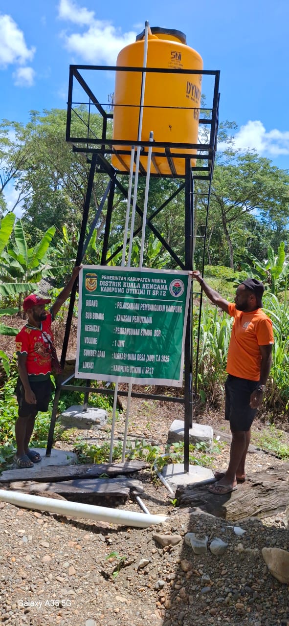 Dua orang warga saat memperlihatkan spanduk kegiatan pembuatan sumur bor