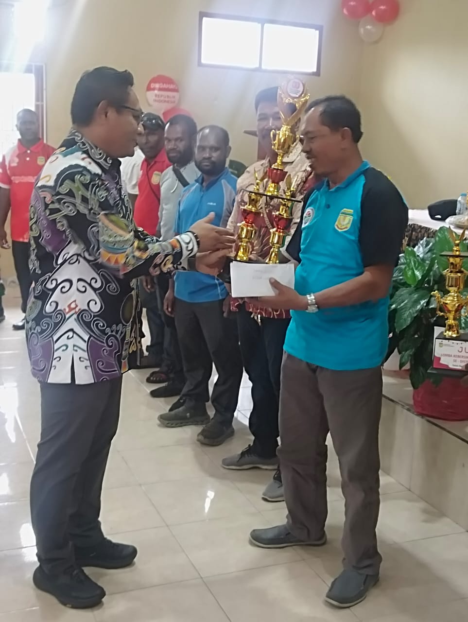 Kepala Kampung Karya Kencana, Rakam Suntoro saat menerima piala dari Kabag Tata Pemerintahan Setda Kabupaten Mimika, Dedi Paukuma