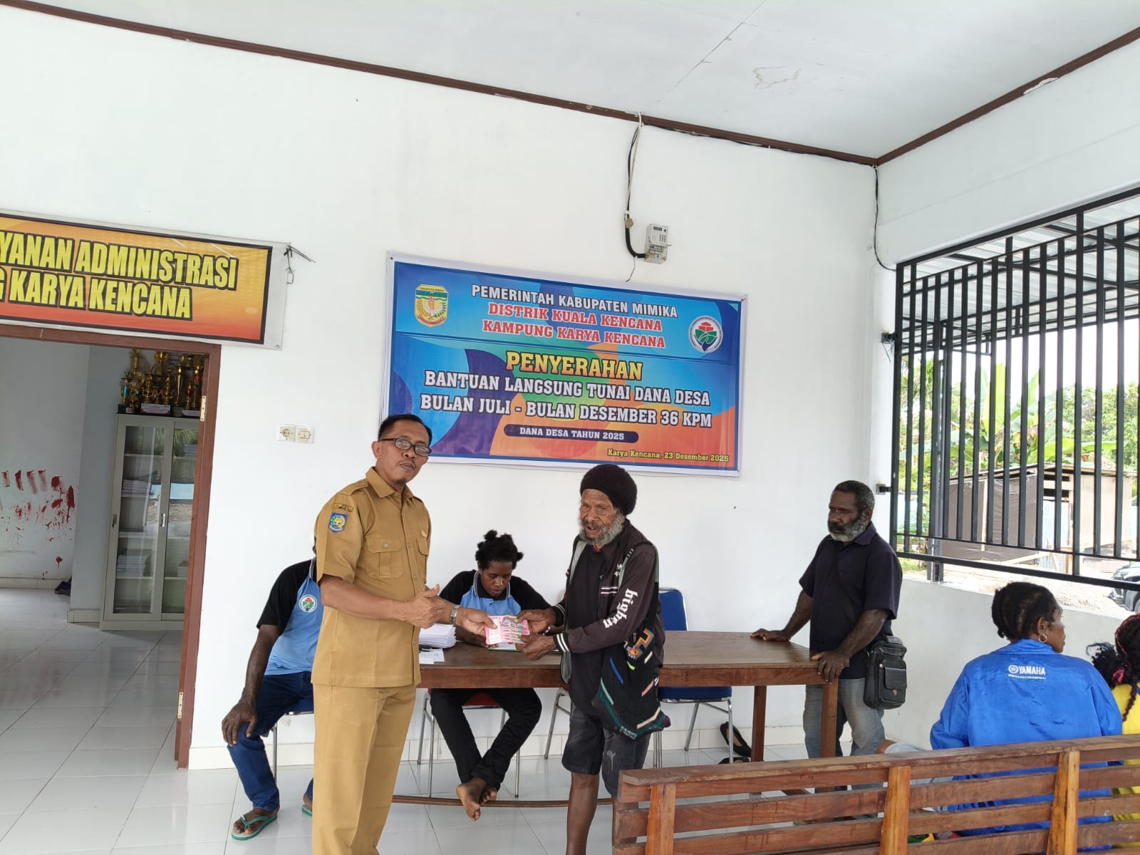 Kepala Kampung Karya Kencana Rakam Suntoro saat menyerahkan BLT kepada warga 