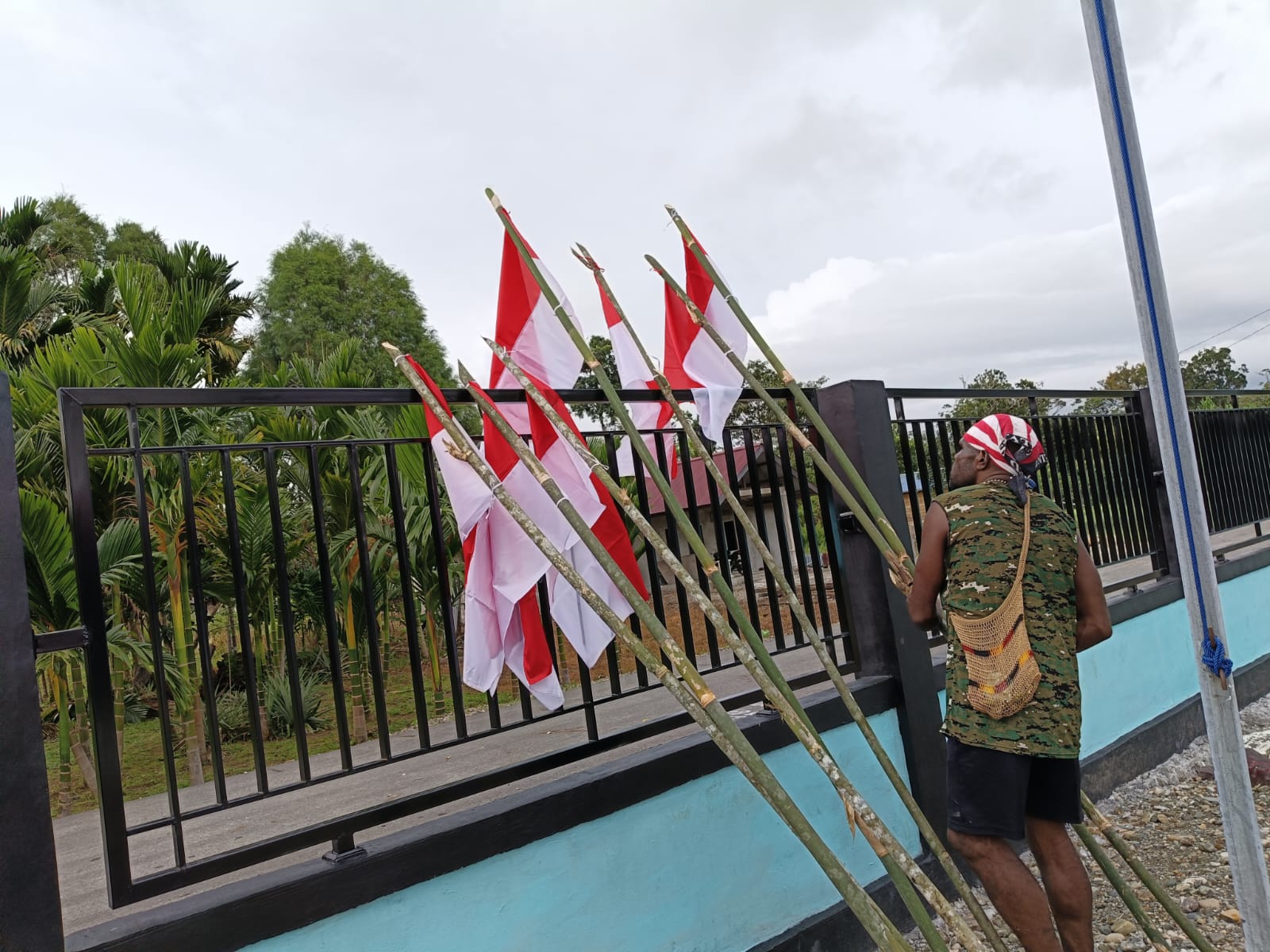 Warga saat mengikat bendera merah putih pada sebuah kayu dan kemudian akan ditancapkan dipinggir jalan