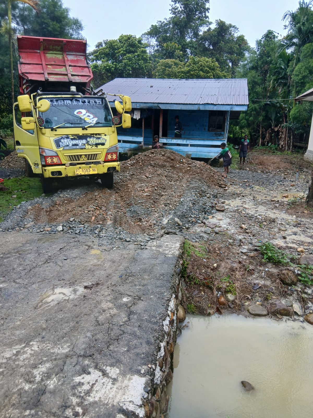 Sebuah truk saat menumpahkan material dihalaman rumah warga 