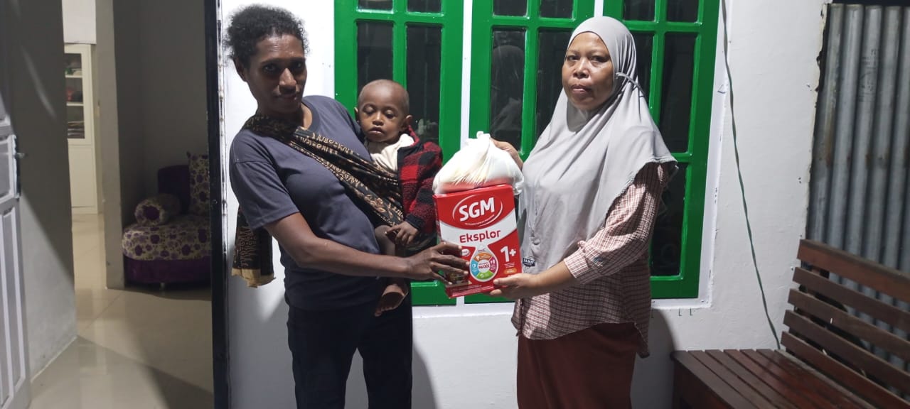 Kader Posyandu saat menyerahkan susu dan makanan tambahan kepada seorang balita