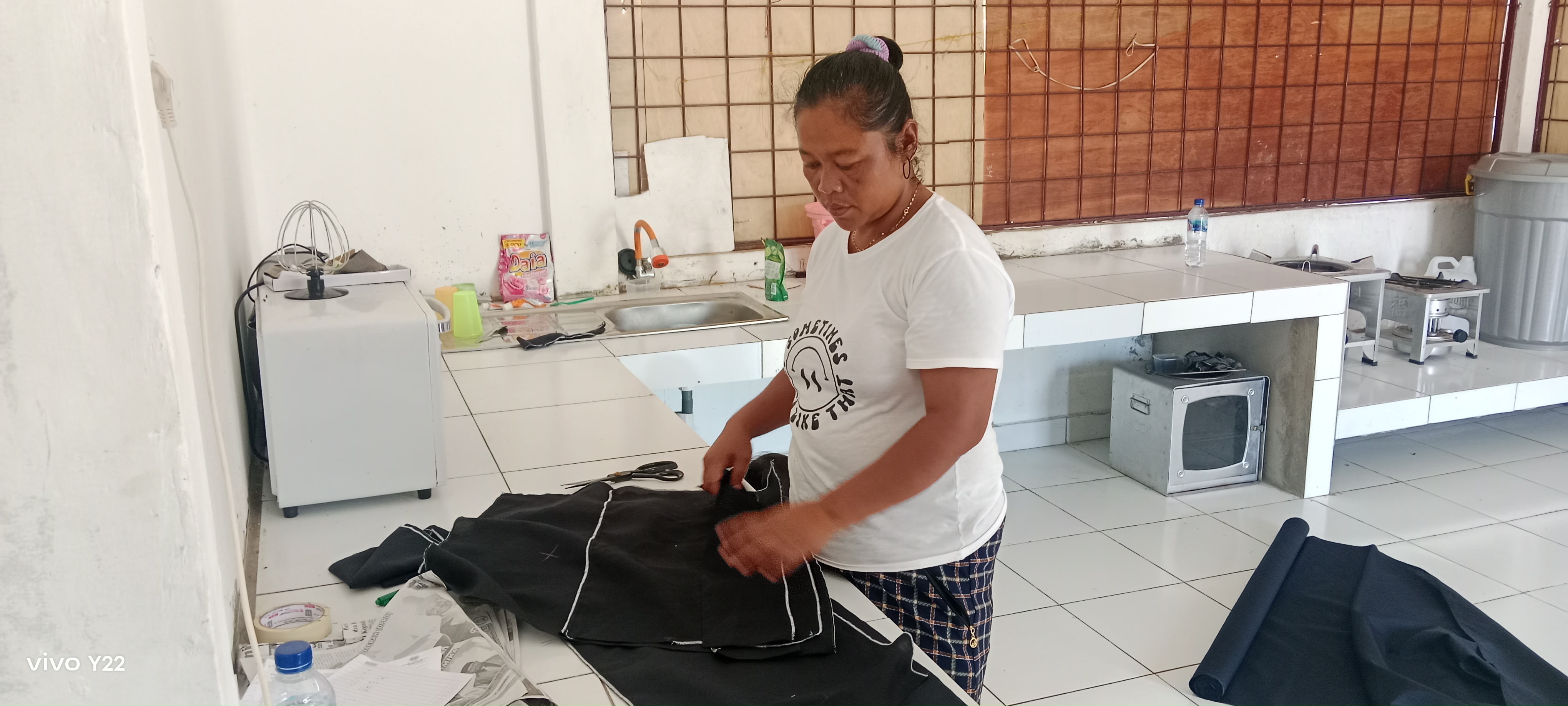 Seorang ibu PKK Kampung Utikini Satu saat mengukur kain untuk kemudian dipotong