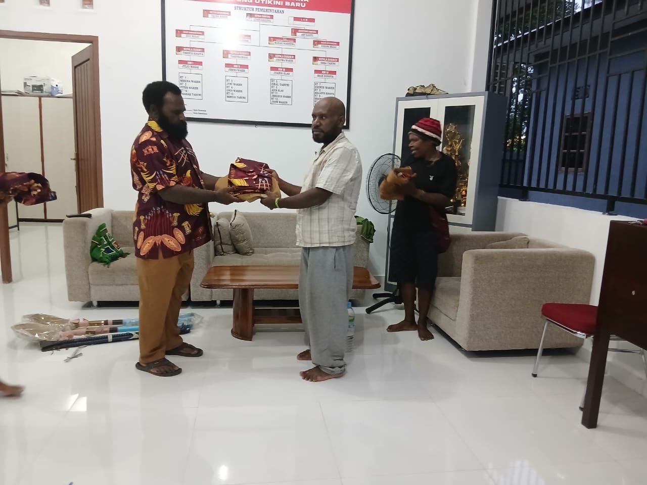 Kepala Kampung Utikini I saat menyerahkan kemeja kepada warganya
