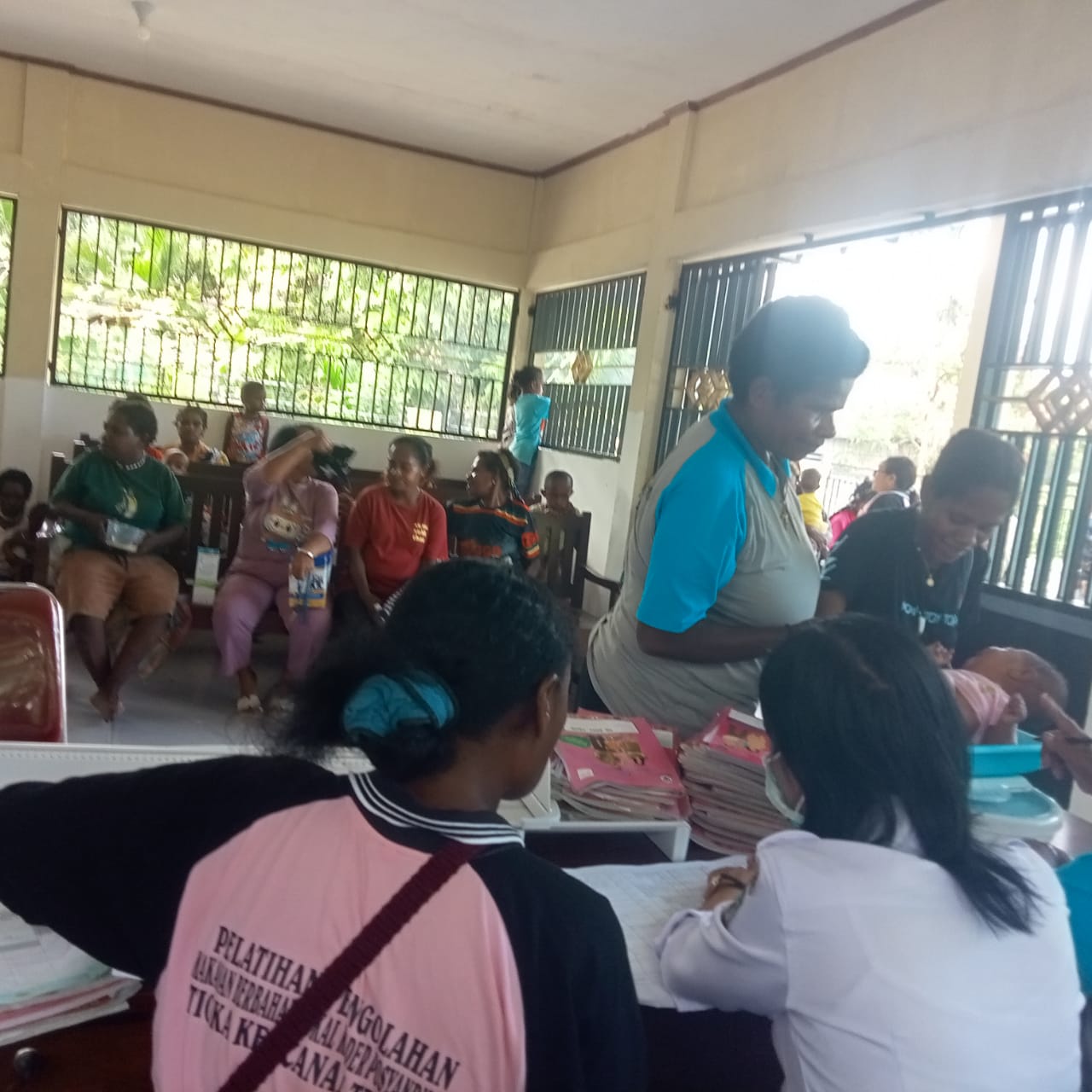 Seorang ibu saat meletakan anaknya diatas timbangan disaksikan ibu kader posyandu