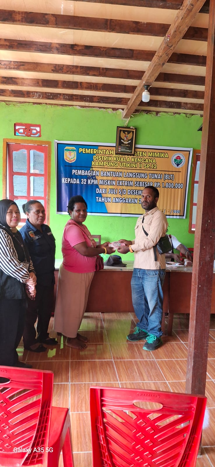 Kepala Kampung Utikini II, Merinus Kogoya didampingi pendamping desa saat menyerahkan BLT kepada seorang warga
