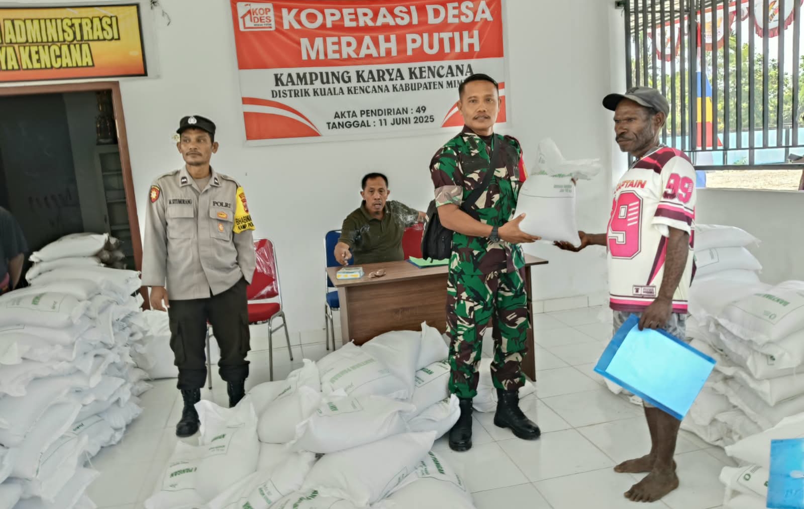 Babinsa Koramil Kuala Kencana menyerahkan bantuan beras kepada warga disaksikan oleh Kepala Kampung Karya Kencana, Rakam Suntoro, Bhabinkamtibmas Kampung Karya Kencana dan warga yang hadir 