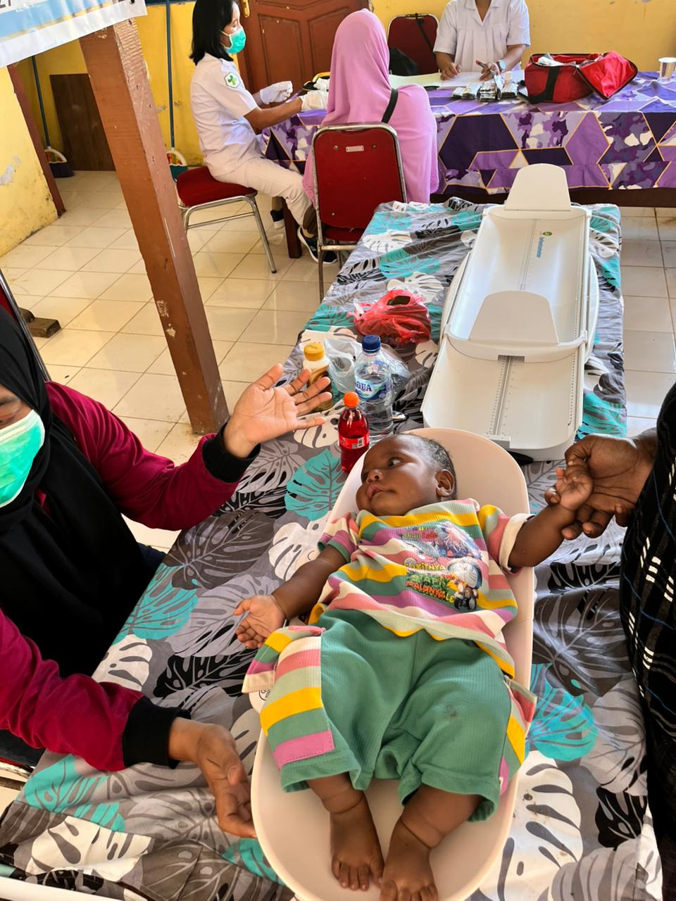 Seorang kader posyandu saat mengukur tinggi badan seorang balita 