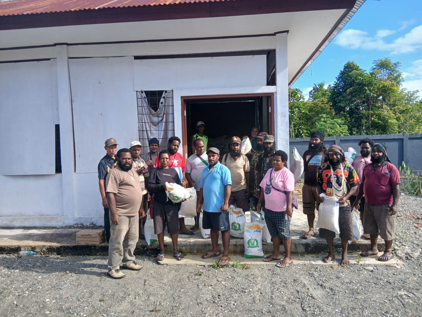 Kepala Kampung Utikini Satu, Luther Karagainal bersama aparatur kampung saat menyerahkan bantuan beras dan minyak goreng kepada warga 