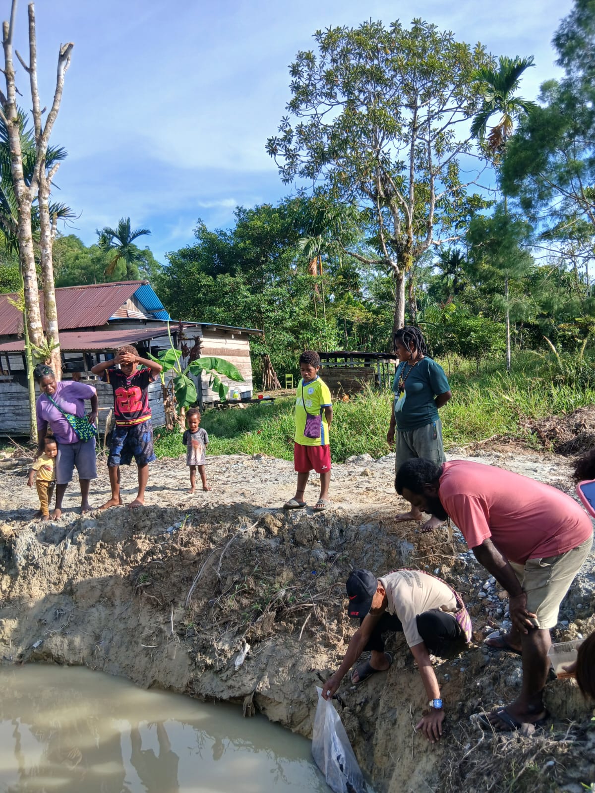 Kepala Kampung Utikini Satu Luther Karagainal bersama Sekertaris Kampung Utikini Satu Arif Karsito saat melepaskan bibit ikan nila kedalam kolam disaksikan oleh warga