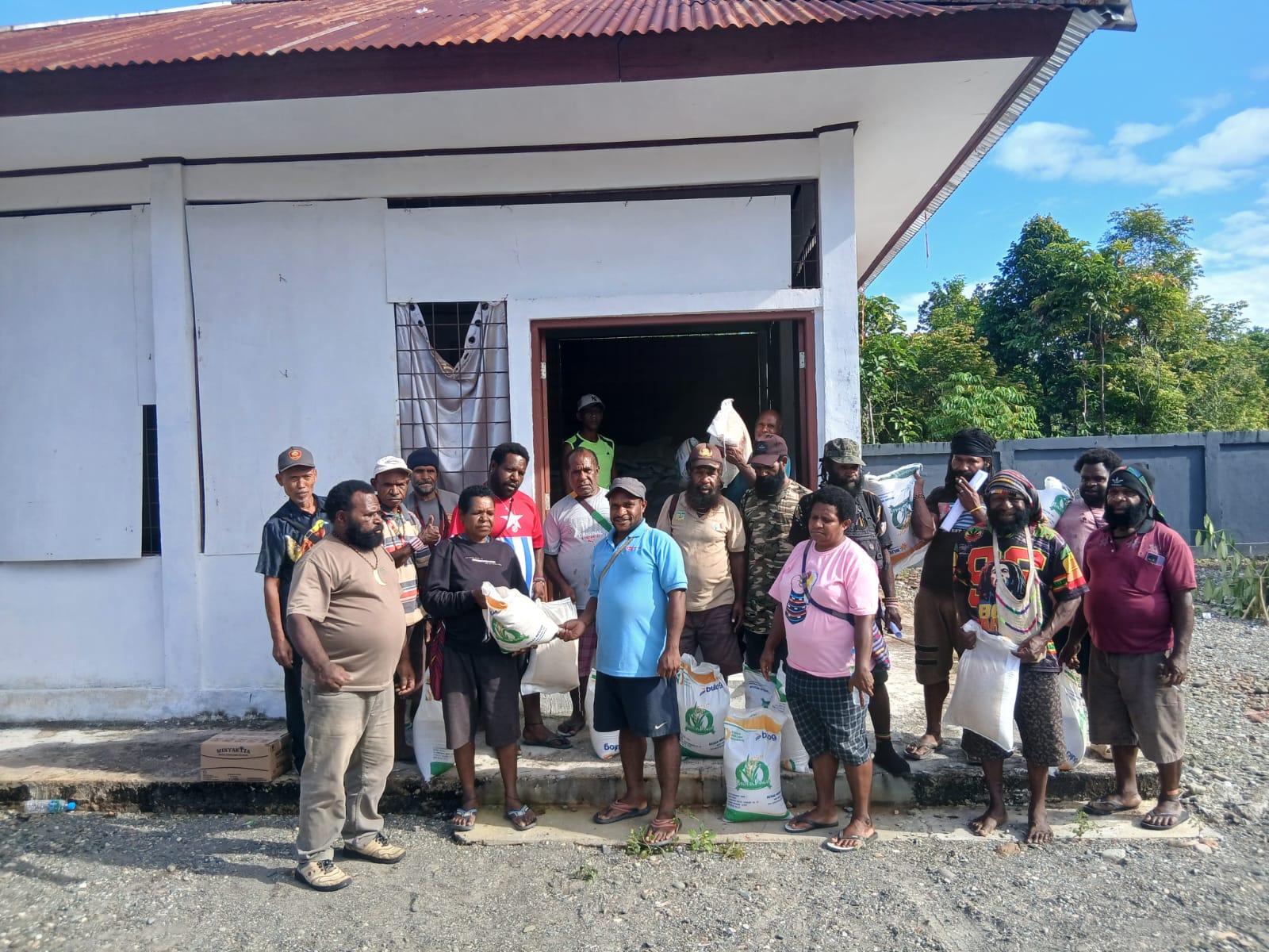 Kepala Kampung Utikini Satu, Luther Karagainal bersama aparatur kampung saat menyerahkan bantuan beras dan minyak goreng kepada warga 