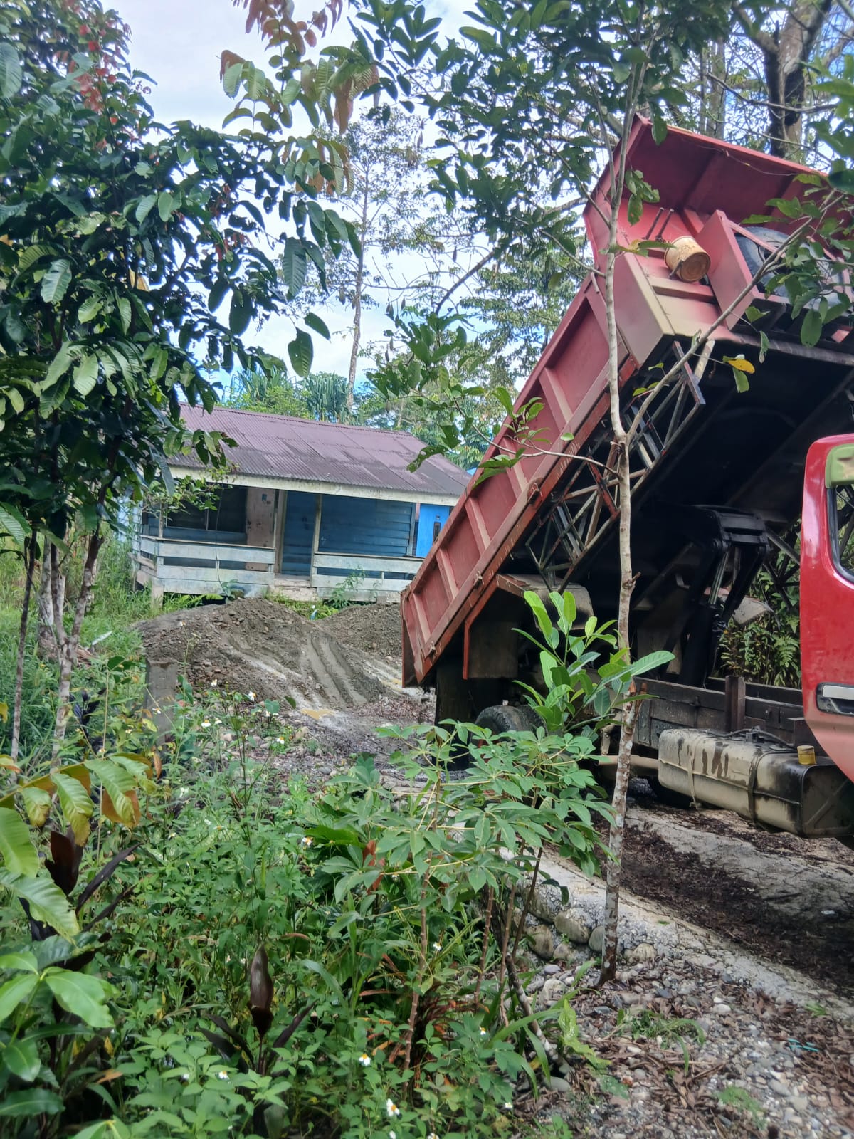 Sebuah truk saat menumpahkan material dihalaman rumah warga 