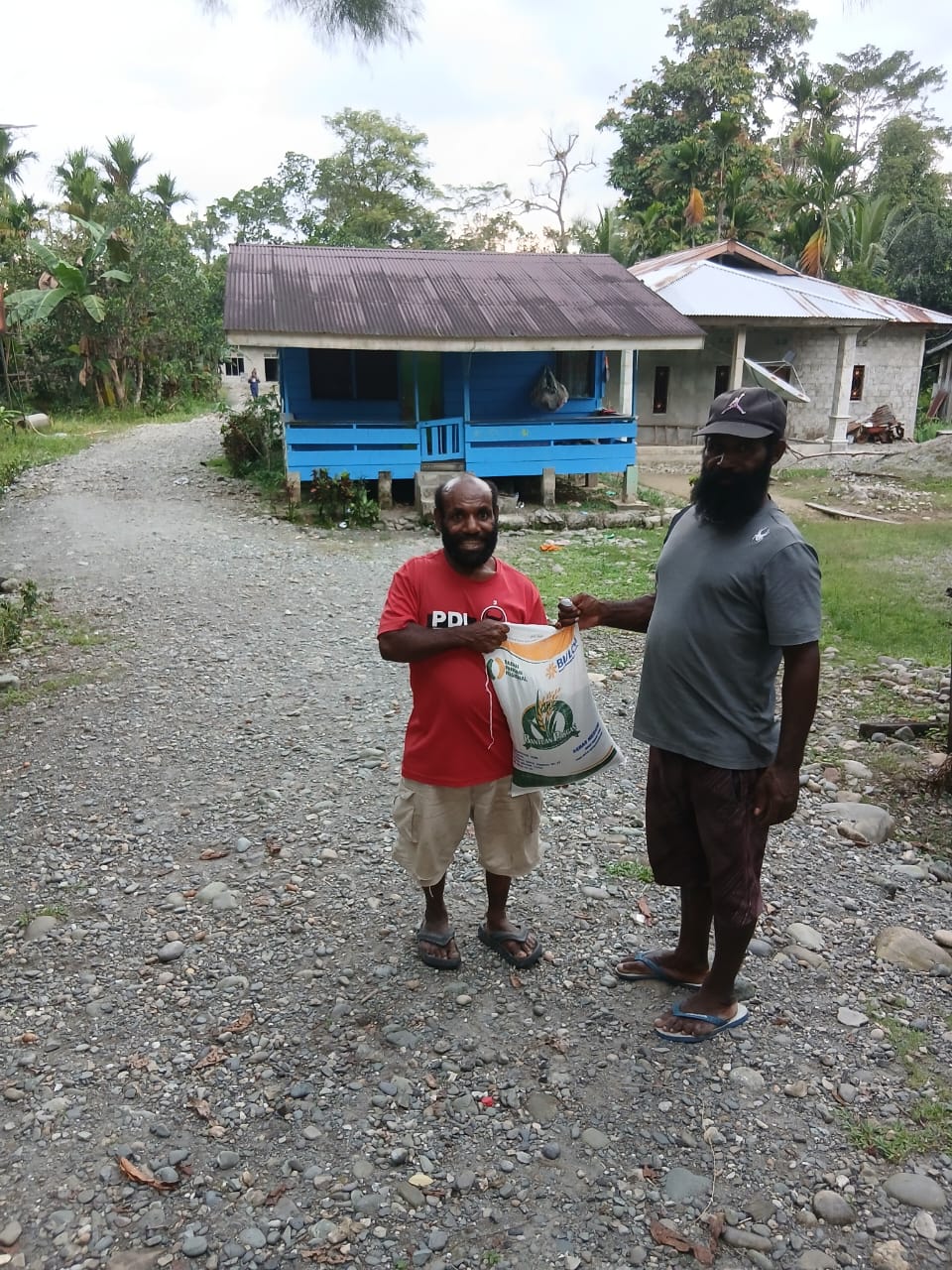 Aparatur Kampung Utikini I saat menyerahkan bantuan beras kepada warga