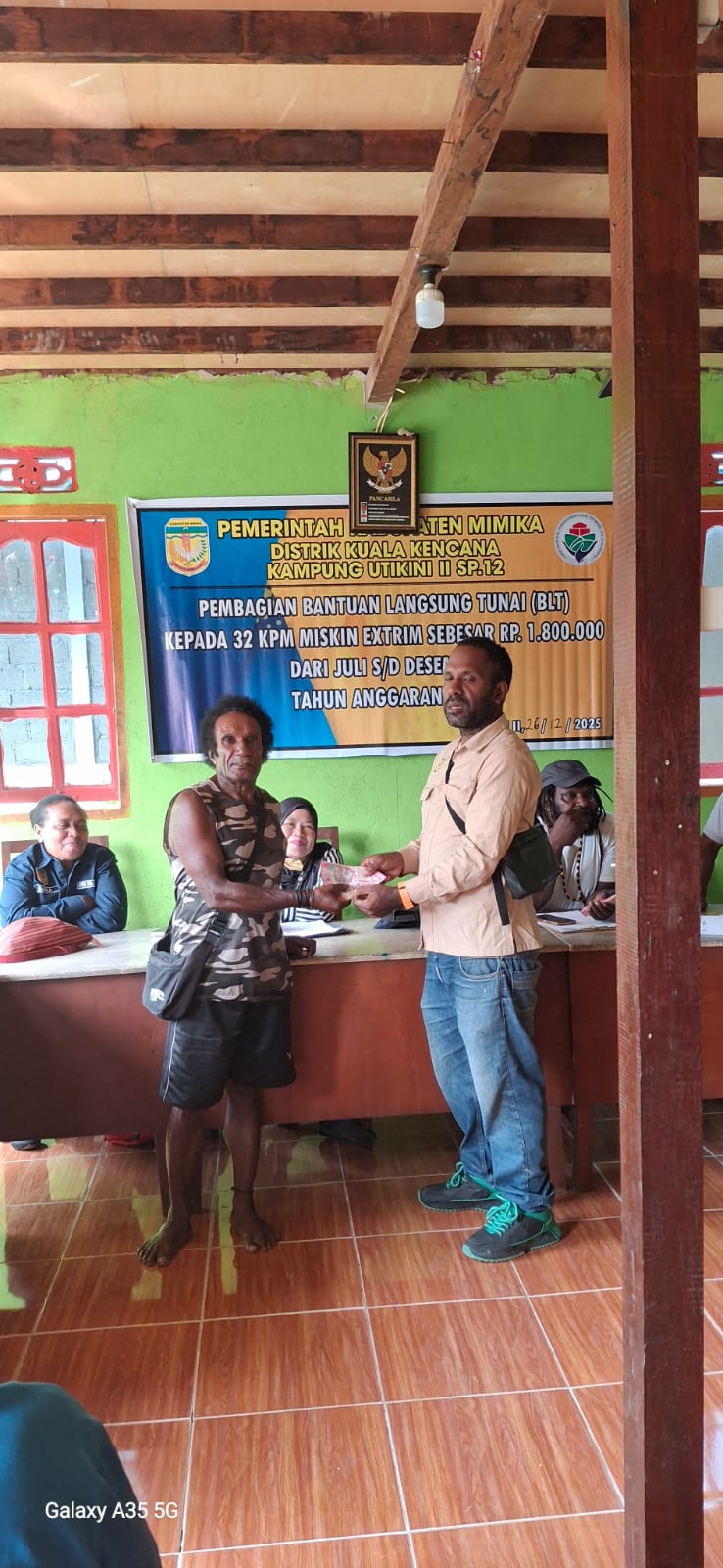 Kepala Kampung Utikini II, Merinus Kogoya didampingi pendamping desa saat menyerahkan BLT kepada seorang warga