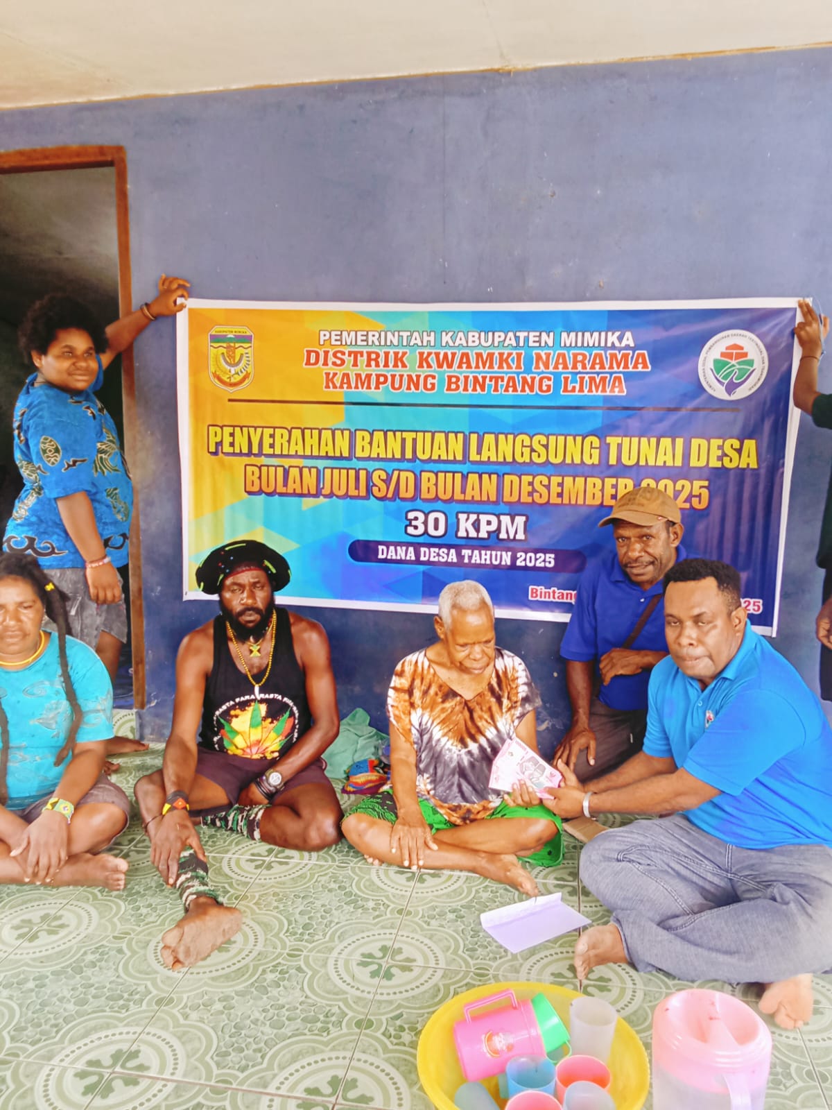 Salah satu aparatur kampung bersama Kepala Kampung Bintang Lima, Marthinus Kogoya saat menyerahkan BLT kepada seorang warga 