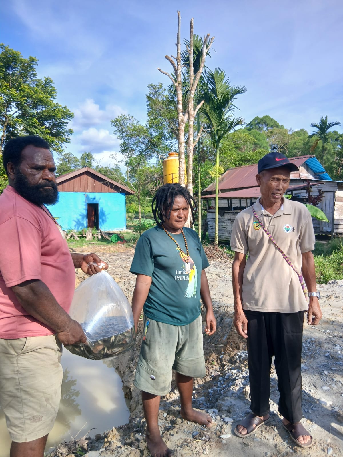 Kepala Kampung Utikini Satu Luther Karagainal bersama Sekertaris Kampung Utikini Satu Arif Karisto saat menyerahkan bibit ikan nila kepada warga 