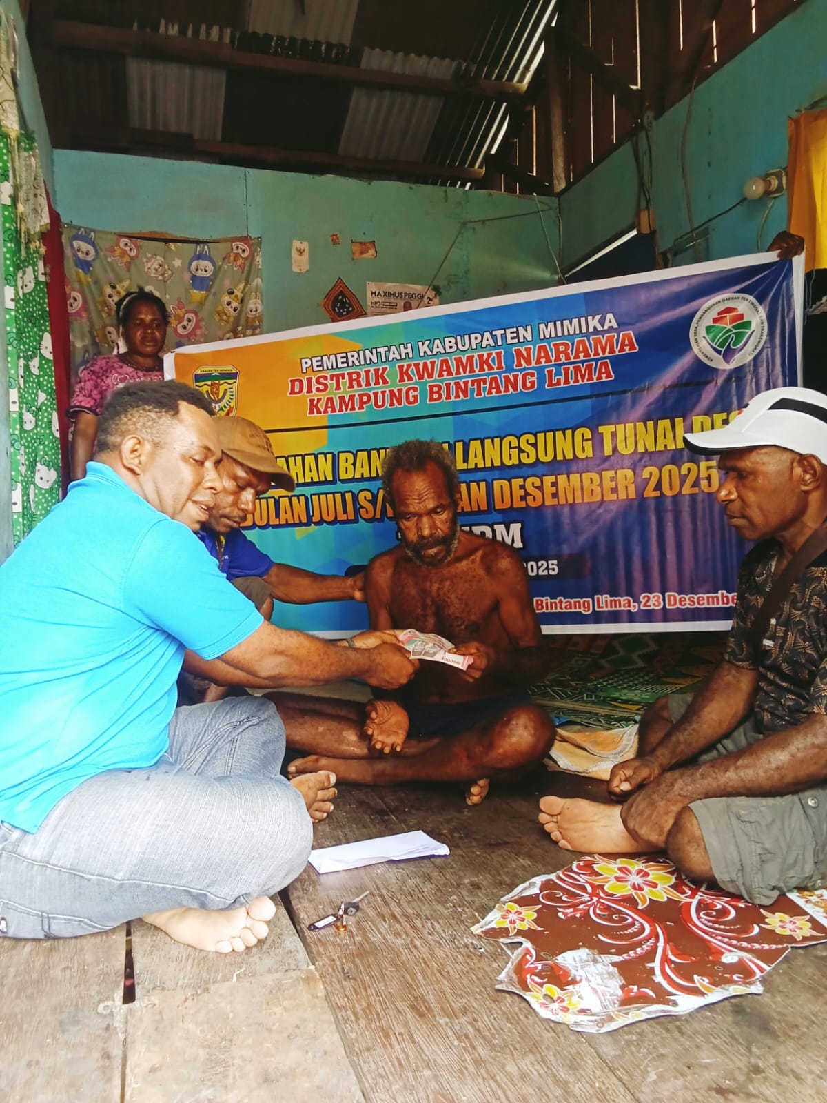 Salah satu aparatur kampung bersama Kepala Kampung Bintang Lima, Marthinus Kogoya saat menyerahkan BLT kepada seorang warga 
