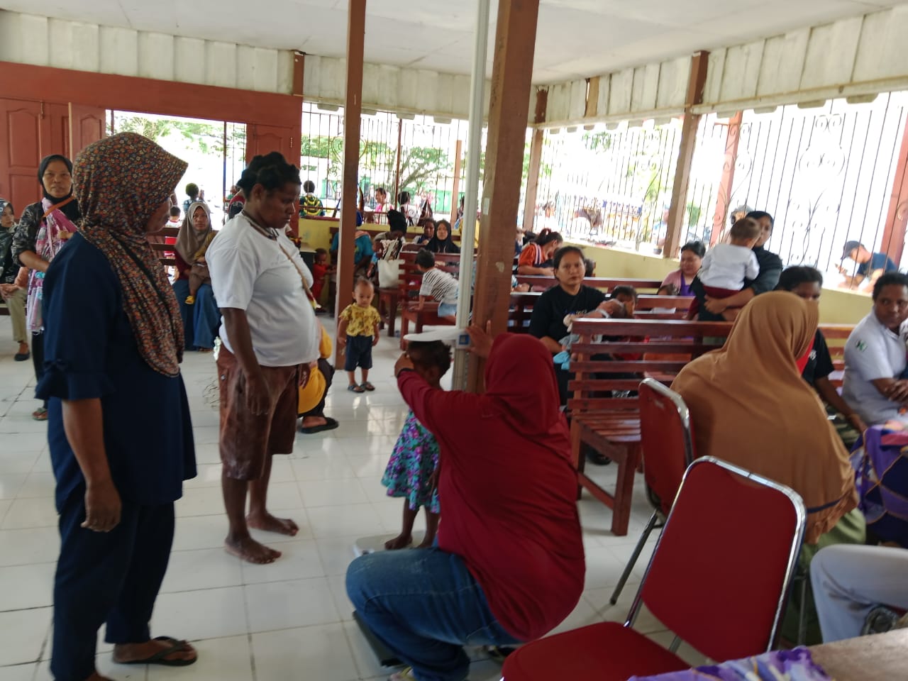 Seorang kader posyandu saat mengukur tinggi badan dari seorang balita