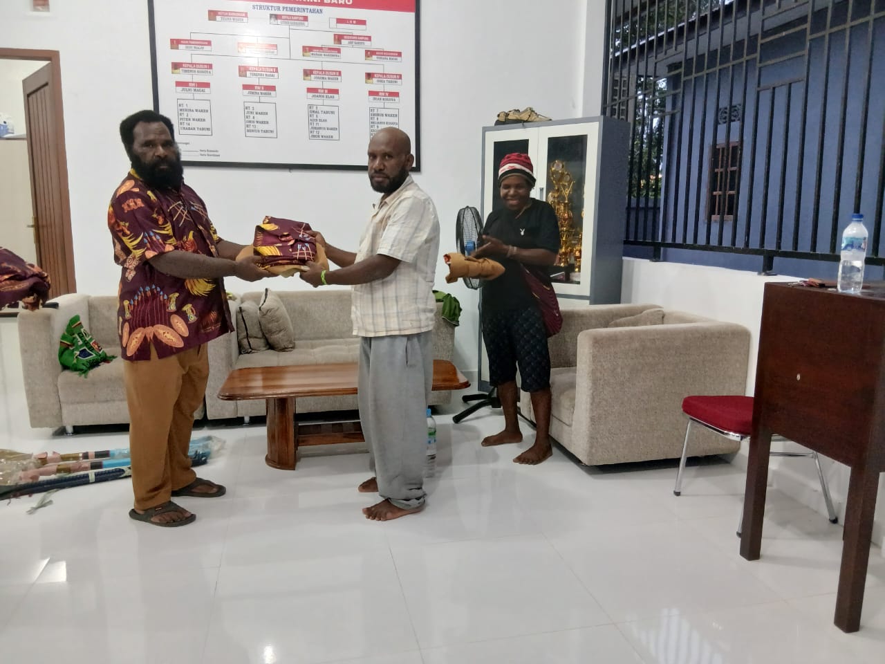 Kepala Kampung Utikini I saat menyerahkan kemeja kepada warganya